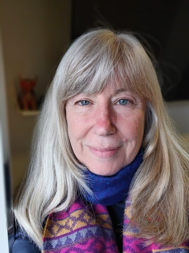 It's portrait of me. I have a sun burnt nose, blonde hair, and I am wearing a jewel coloured scarf